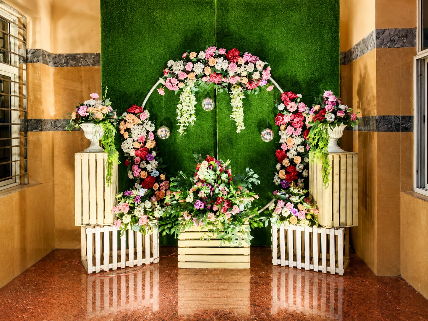 Green grass wall floral archway with pastel roses and rustic wooden pedestals