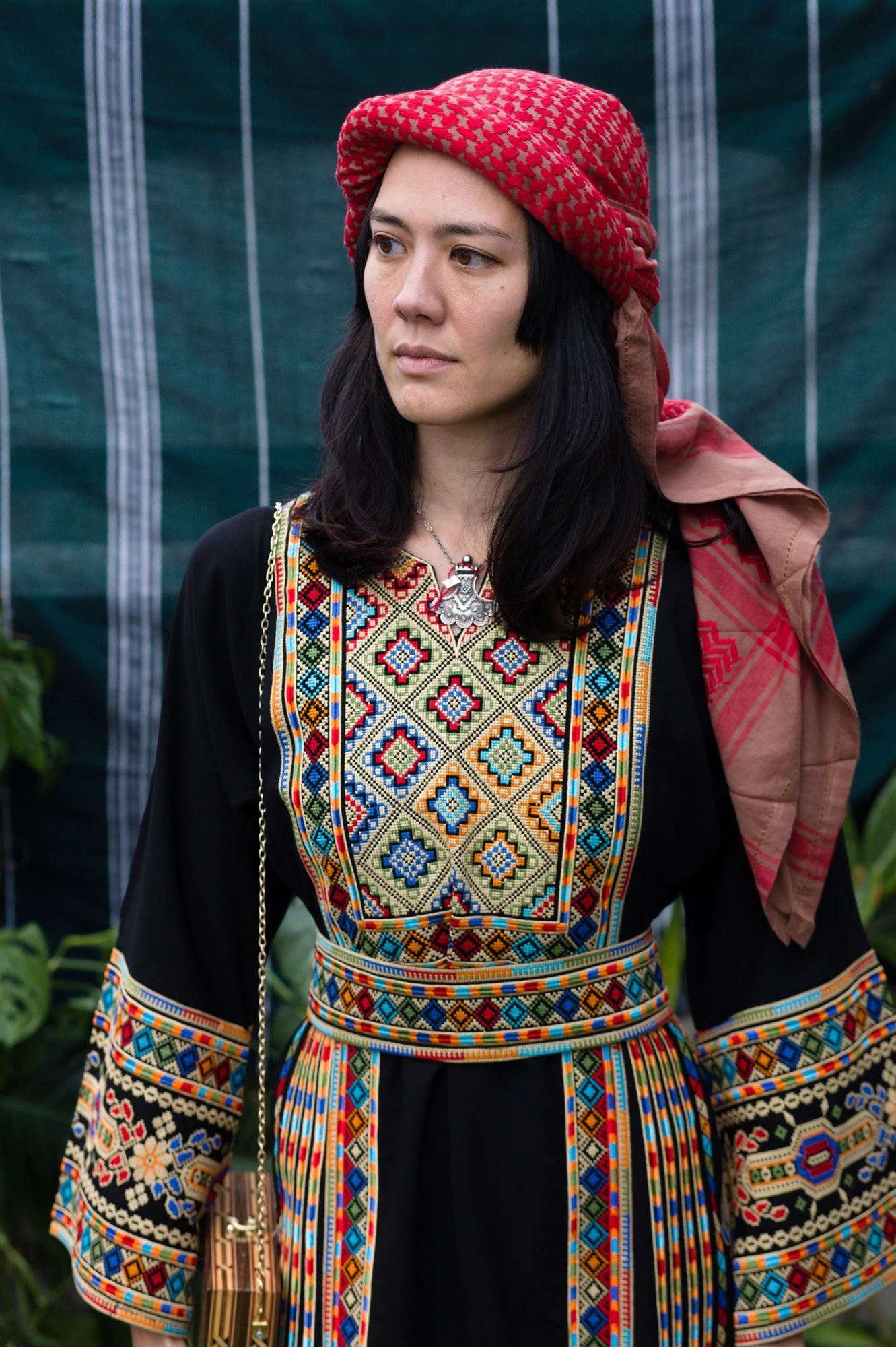 Femme portant une robe noire richement brodée de motifs multicolores.