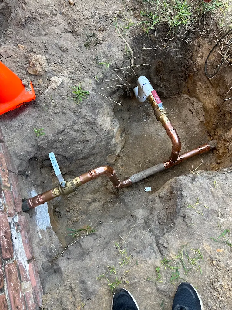 Copper pipe repair and backflow valve installation in excavated trench