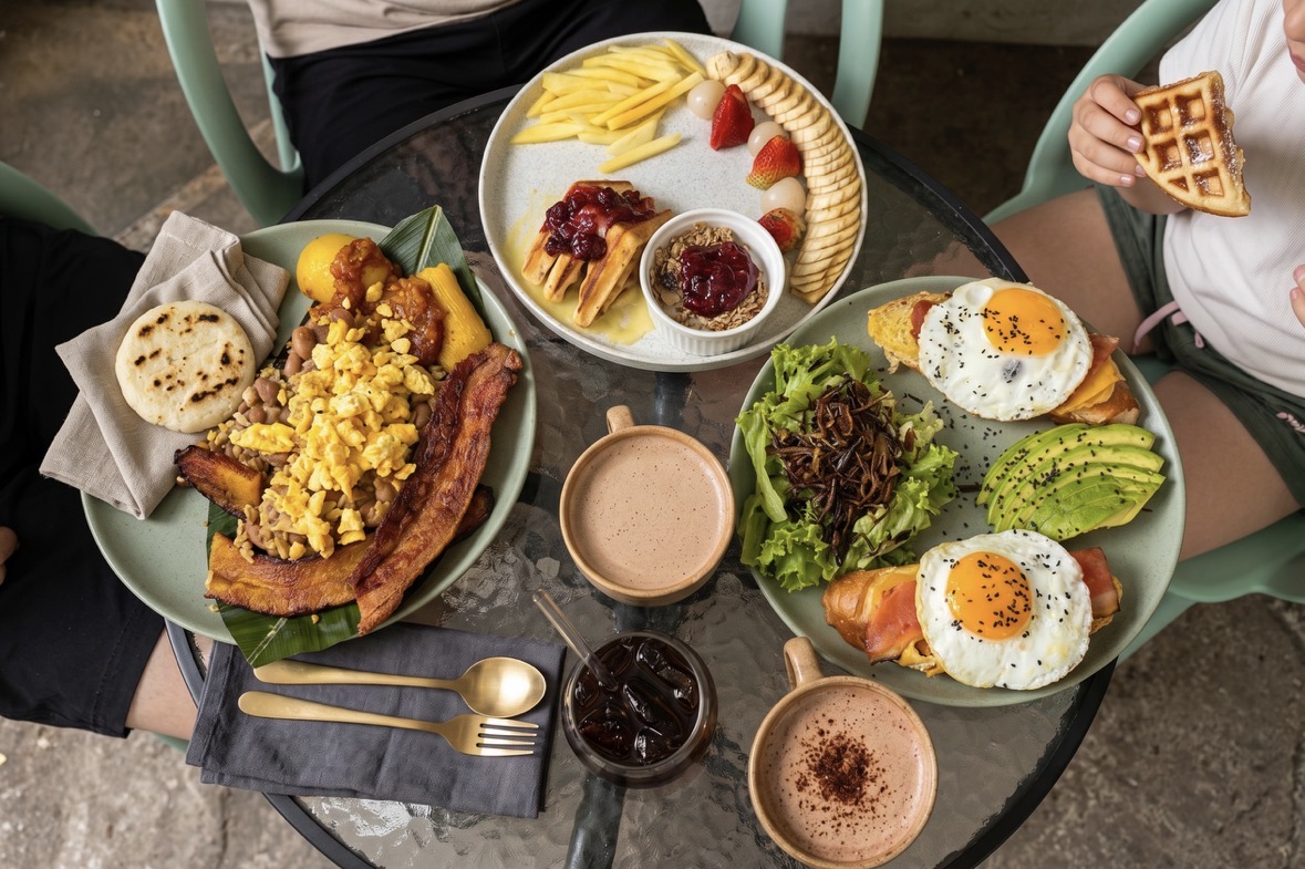 Desayuno típico paisa servido en el restaurante — huevos, bacon, plátano, arepa, waffles y café colombiano