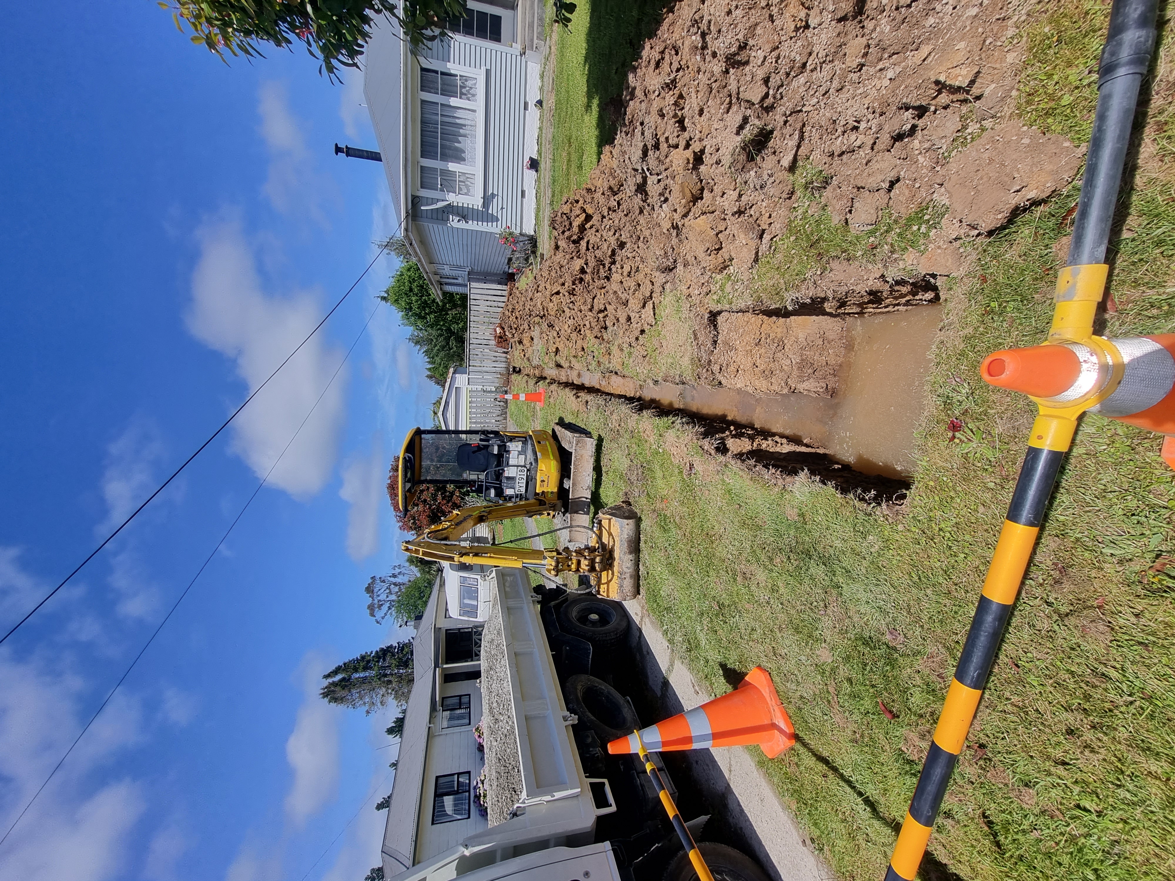 Mini excavator digging a residential trench for water and power, Greymouth