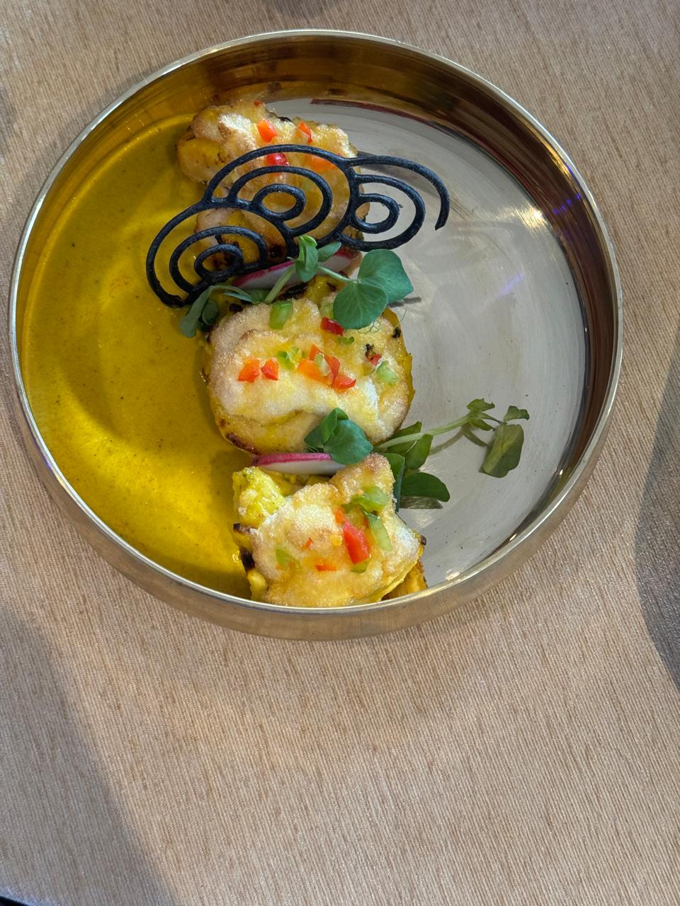 Tikka with black tuile garnish on gold plate