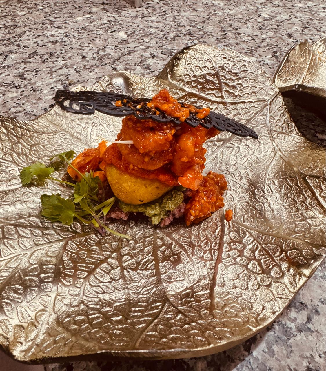 Spicy meat dish on gold leaf-shaped platter