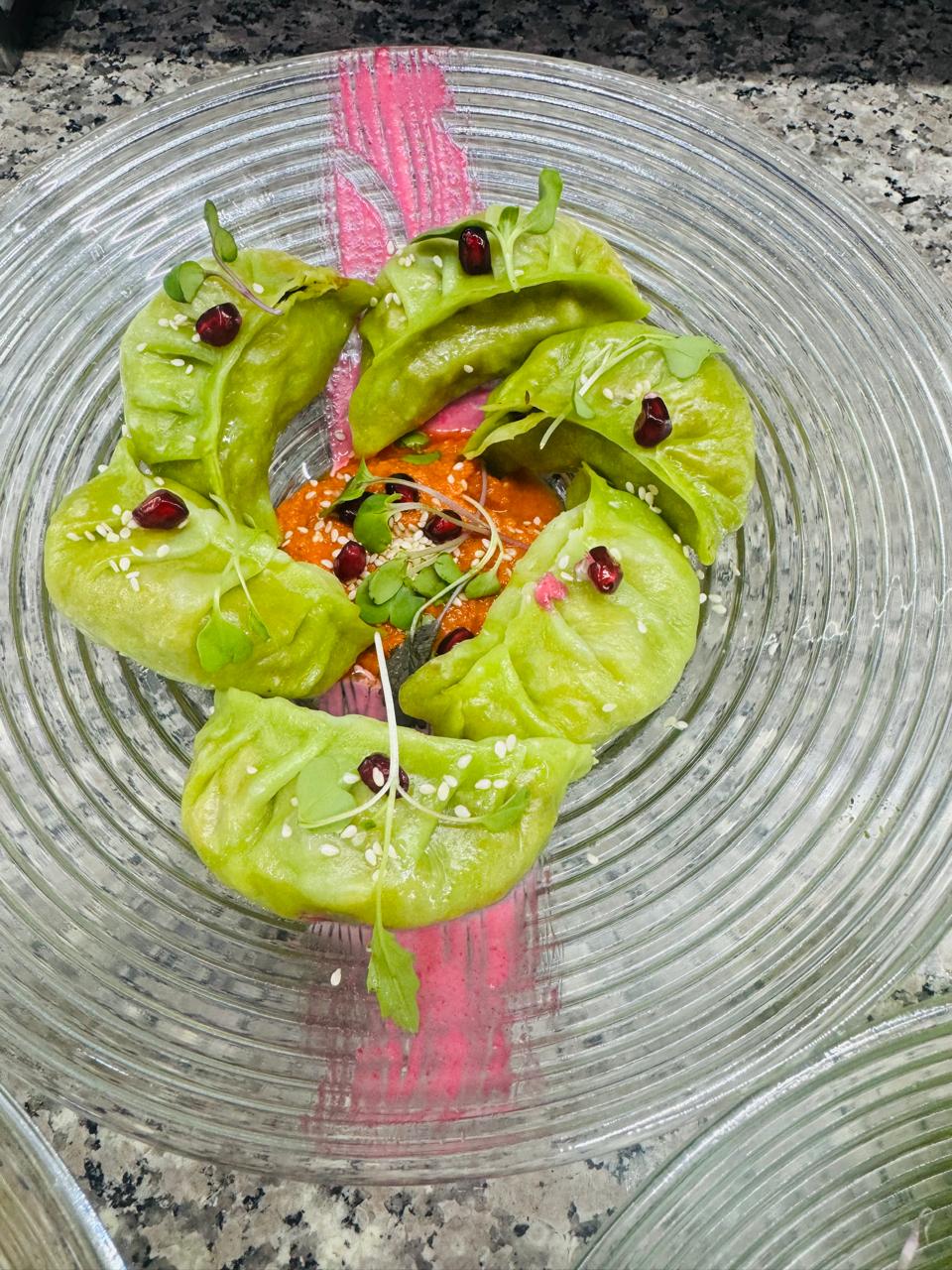 Green momos with pomegranate on glass plate