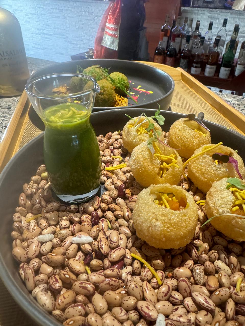 Pani puri shells on heirloom beans with mint shot