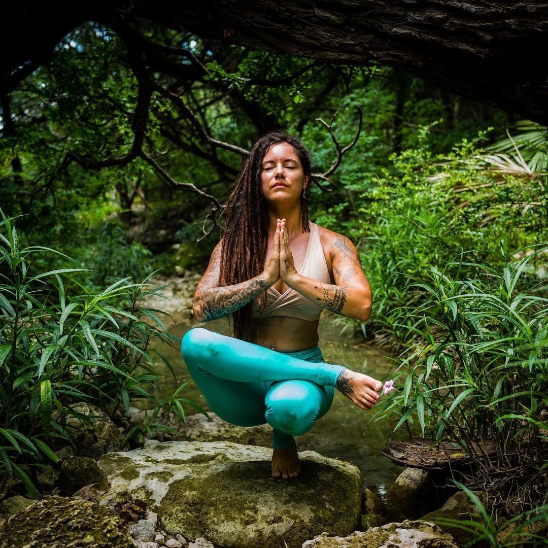 Meditazione yoga su roccia nel ruscello della foresta