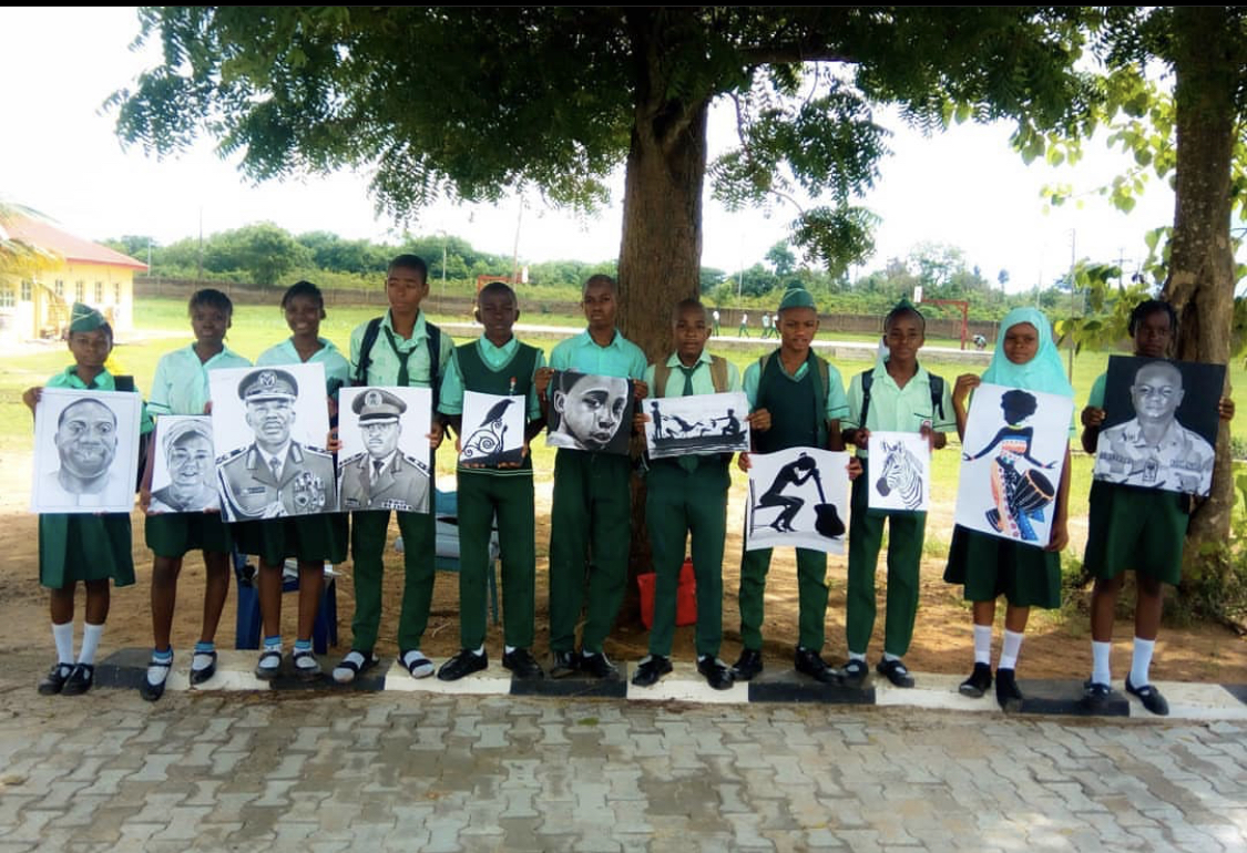 Students displaying charcoal artwork outdoors