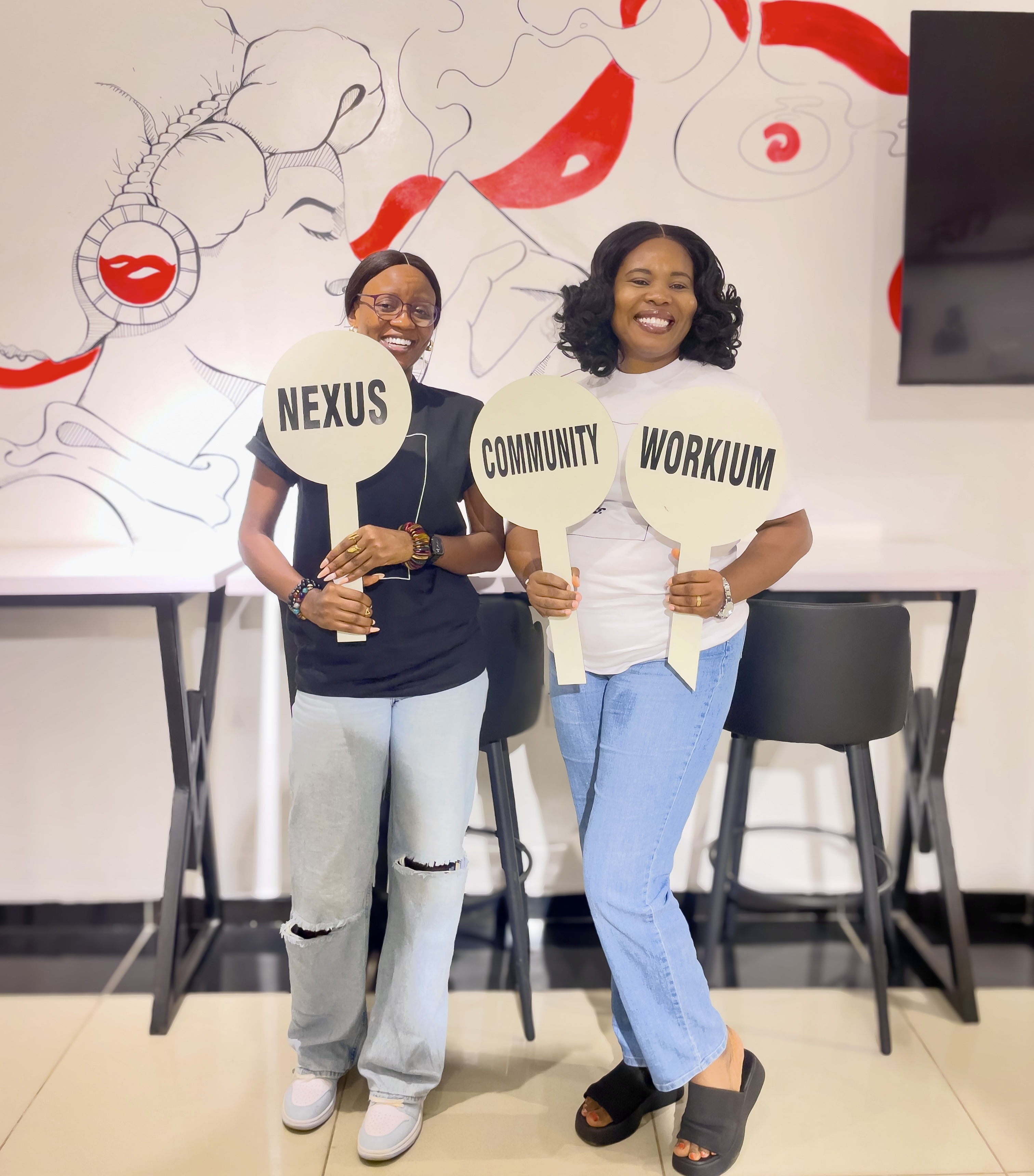 Two Nexus Abuja members holding Workium, Nexus and Community signs