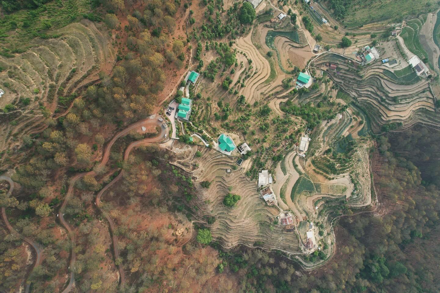 Banpravas from above — green roofs nested into terraced fields, the Kumaon stitched in contour lines