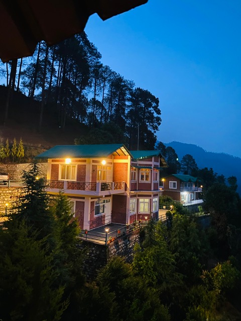 Banpravas — the cottage at blue hour, every window lit against the deodar forest