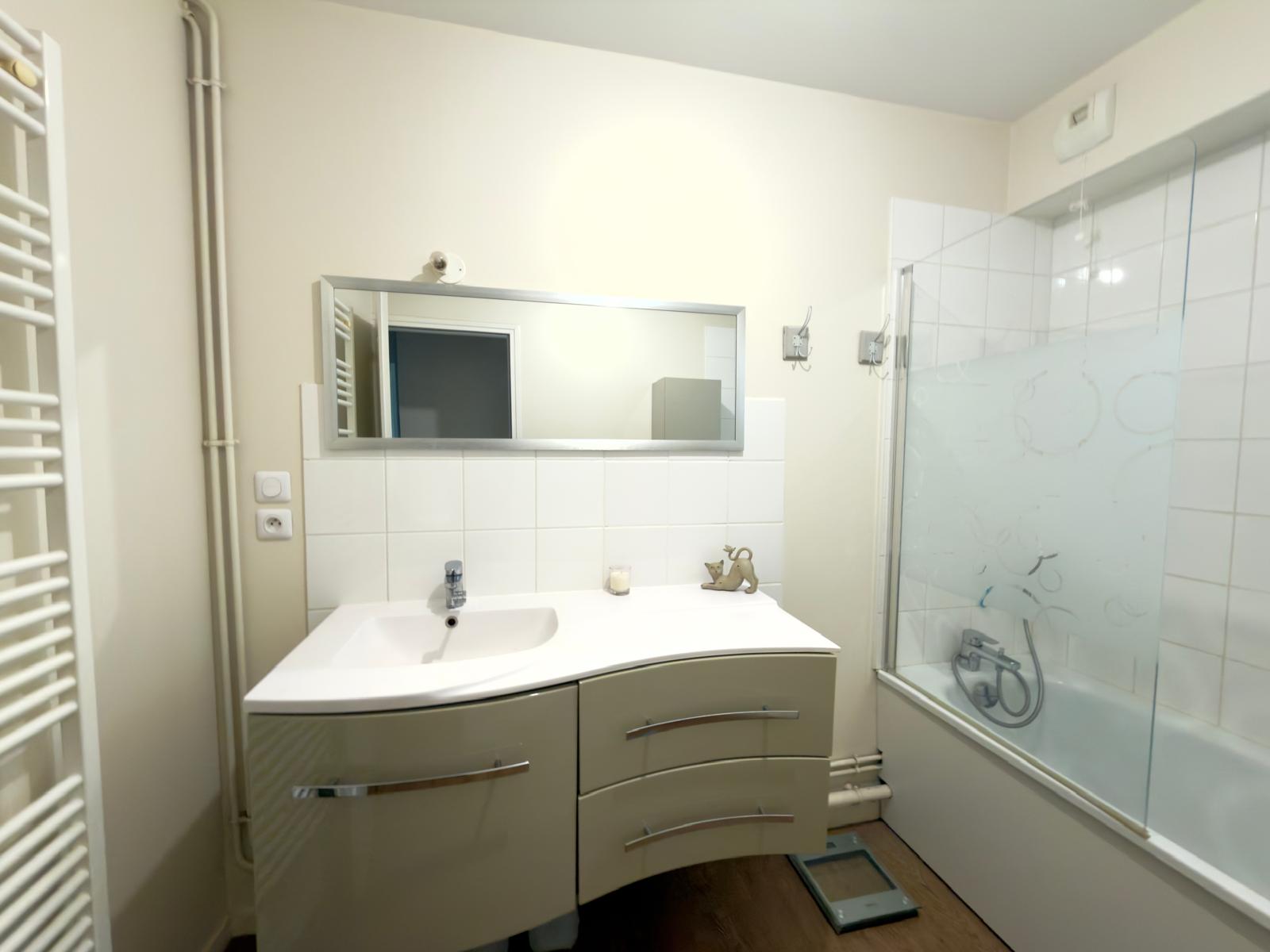 Salle de bain lumineuse avec meuble double vasque, baignoire et sèche-serviettes