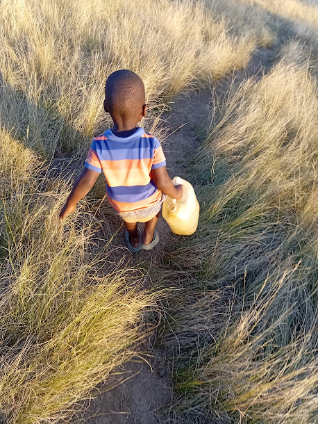 A child walks home with the day's water
