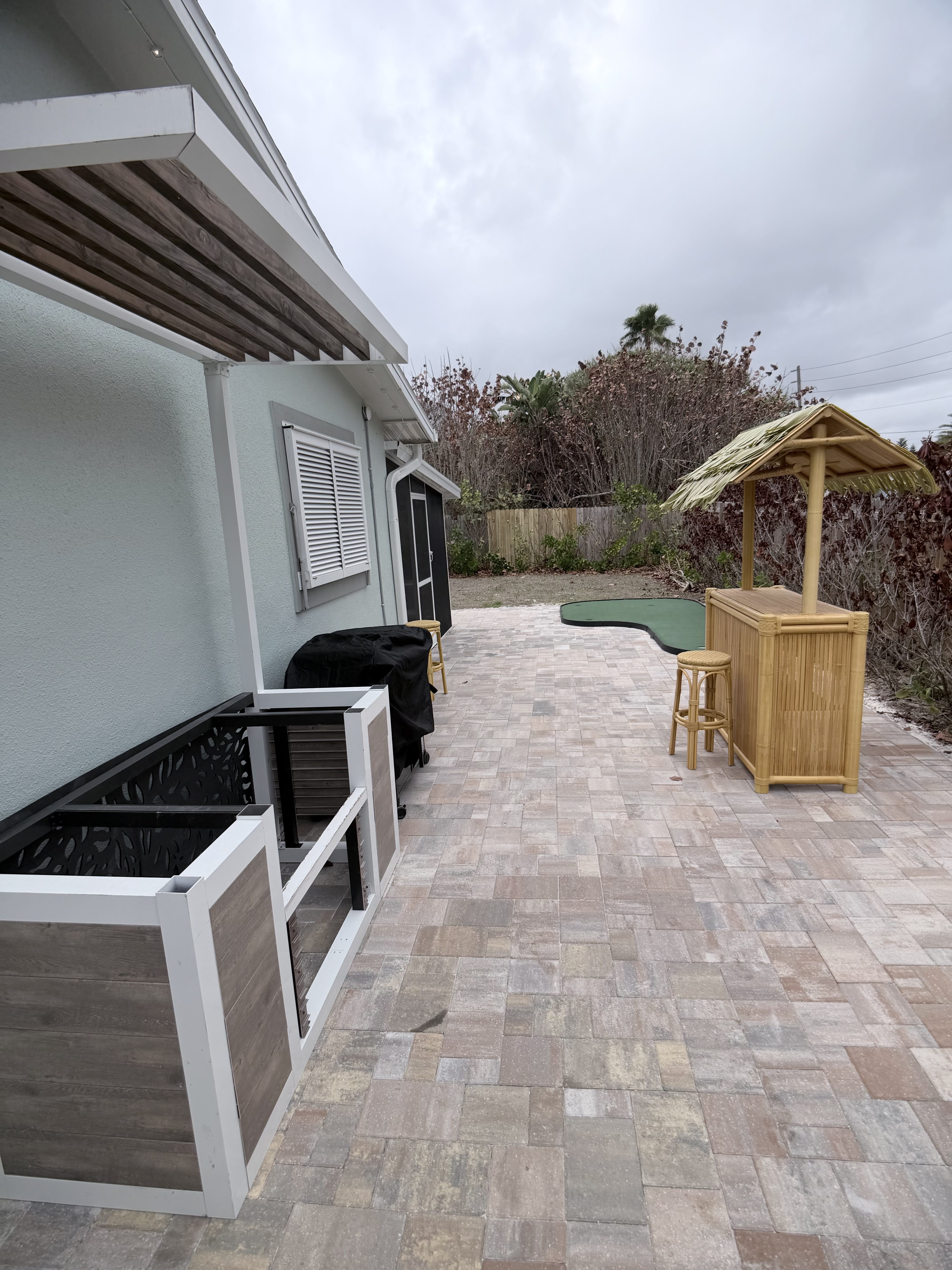 Fenced backyard with tiki bar and putting green