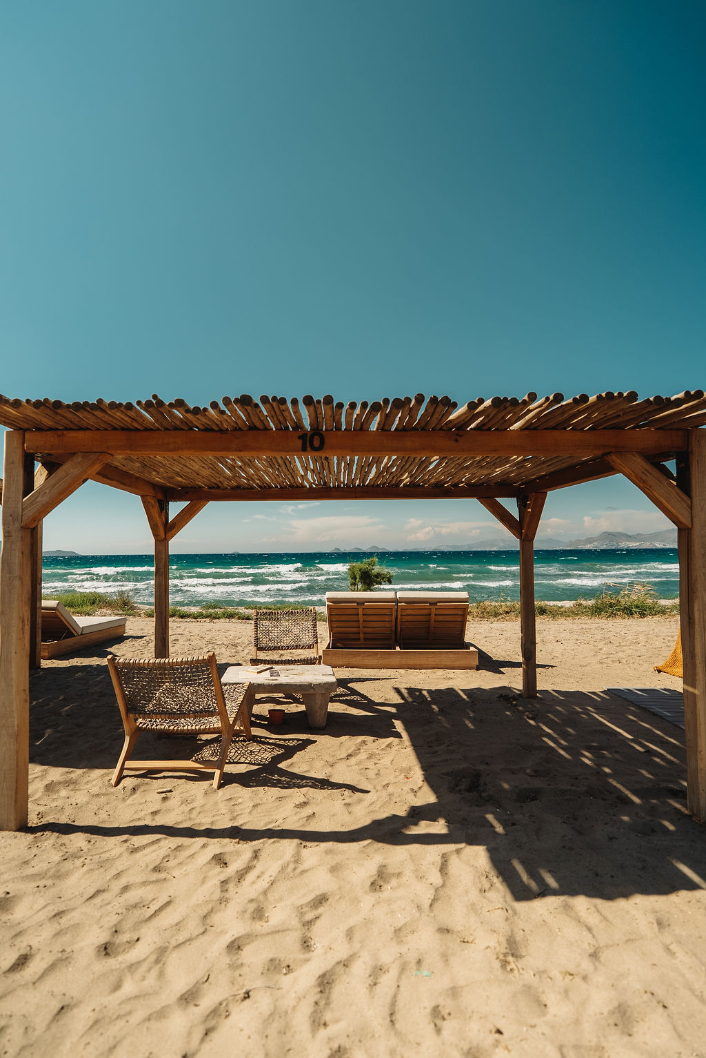 Private daybeds under timber pergolas at Tribe Beach, Tigaki