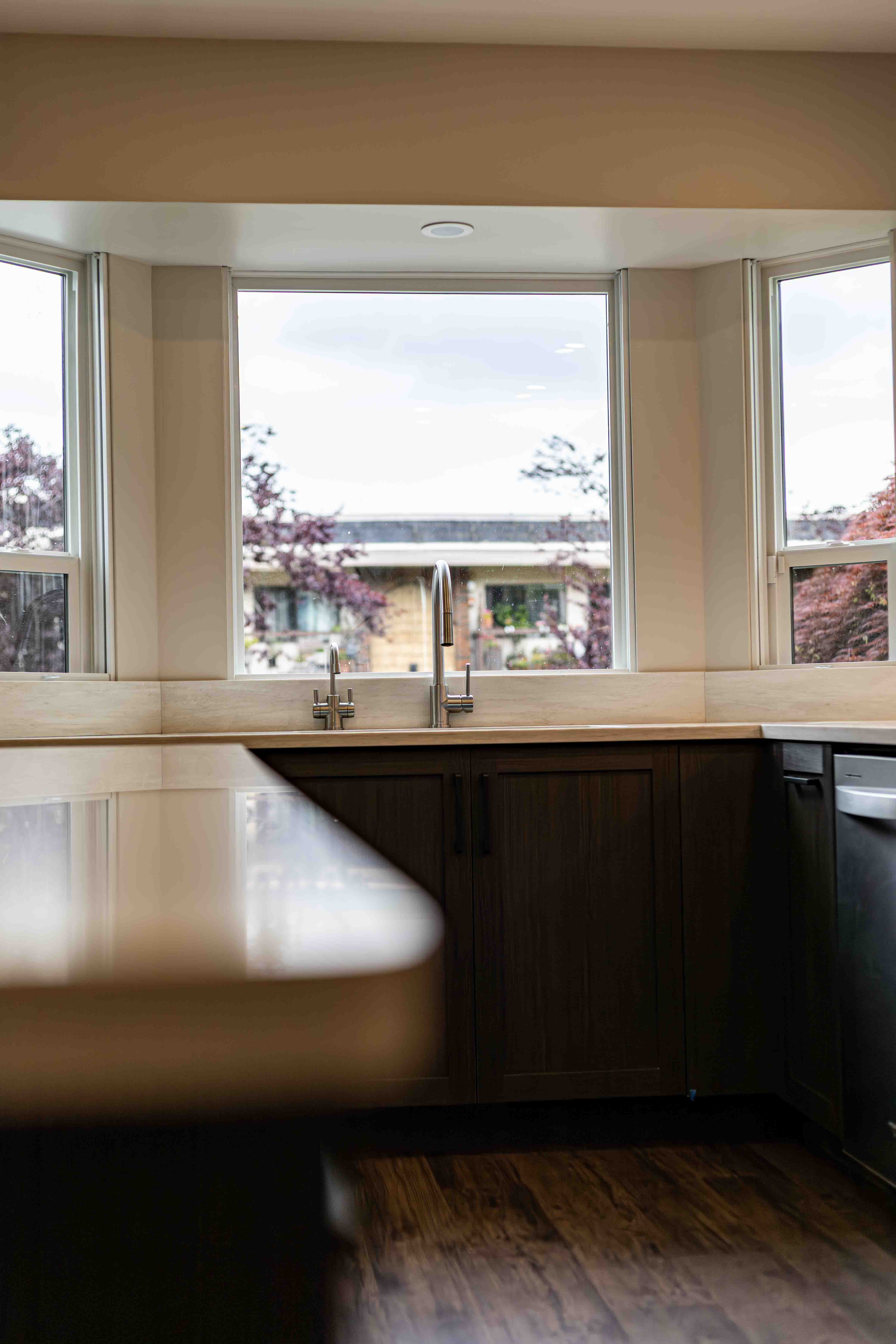 Walnut cabinetry under bay window with brushed nickel faucets — Vancouver designer kitchen renovation