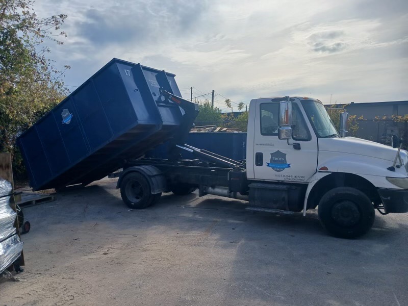 Troya Mini Bins truck lifting a branded blue roll-off bin on a Toronto job site