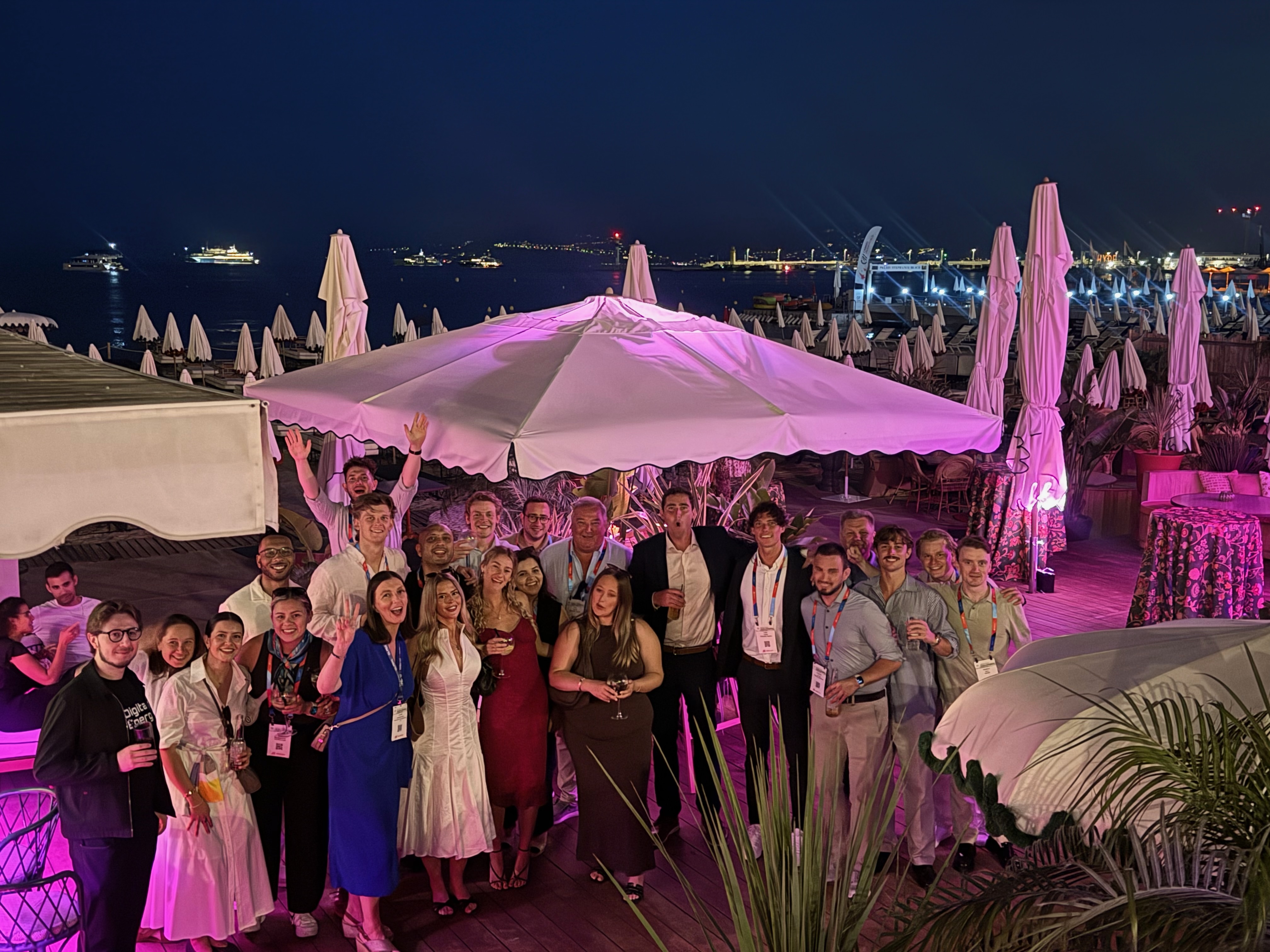 DCYB poster lit pink at night with the Mediterranean and yacht harbor behind it.