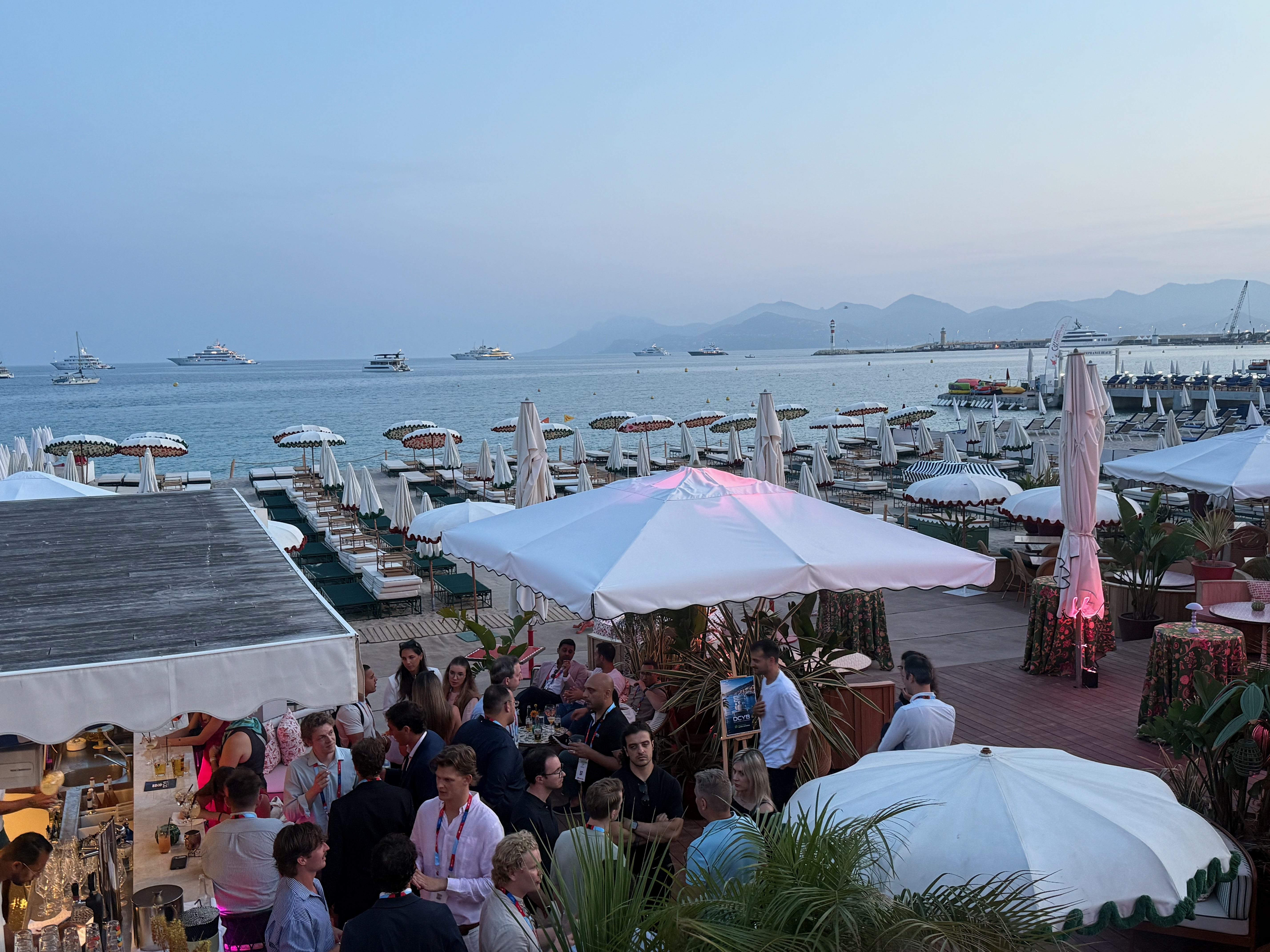DCYB attendees networking under the awning beside the event easel, Cannes 2026.