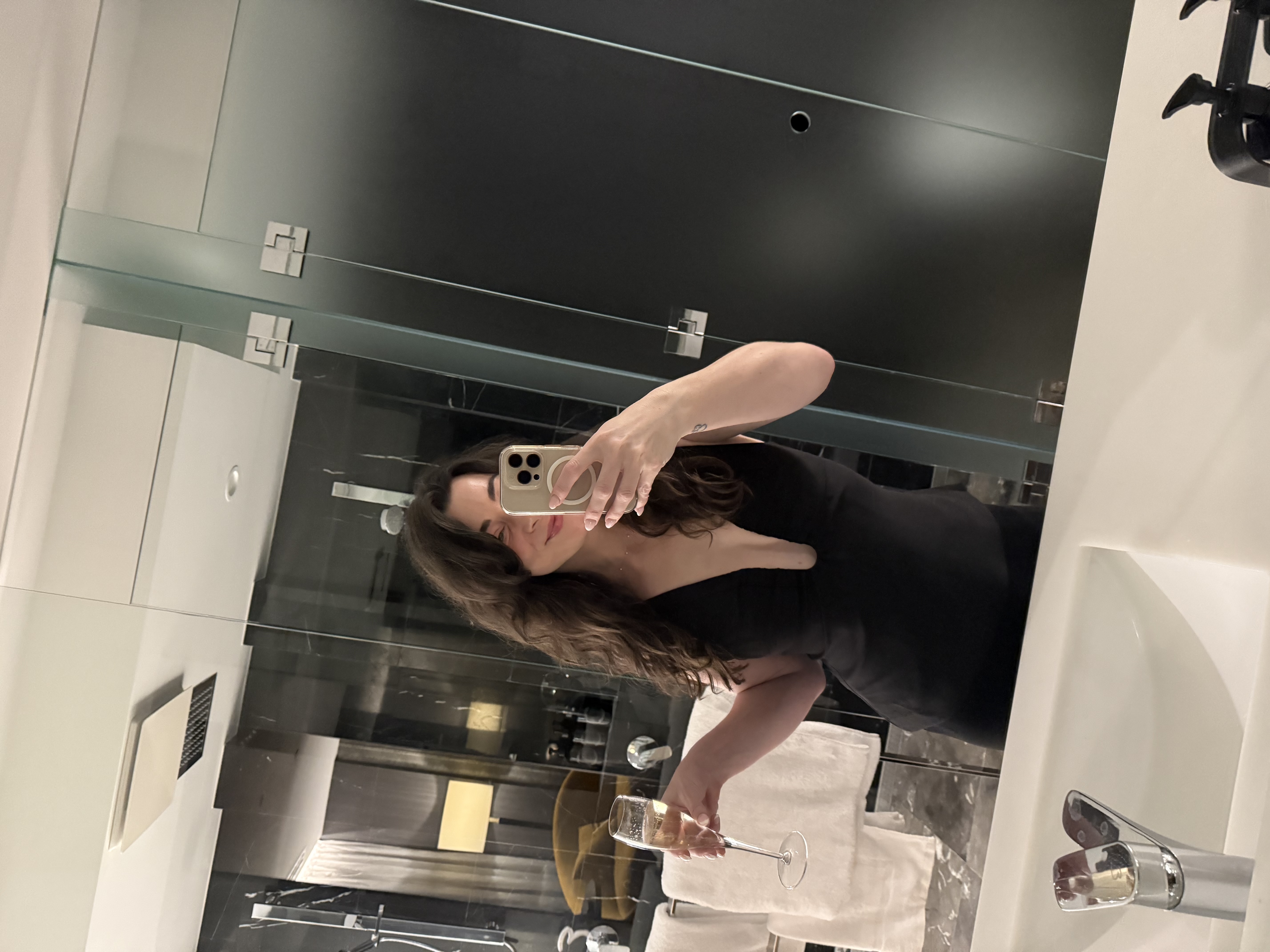 Mirror selfie in a little black dress with a champagne flute