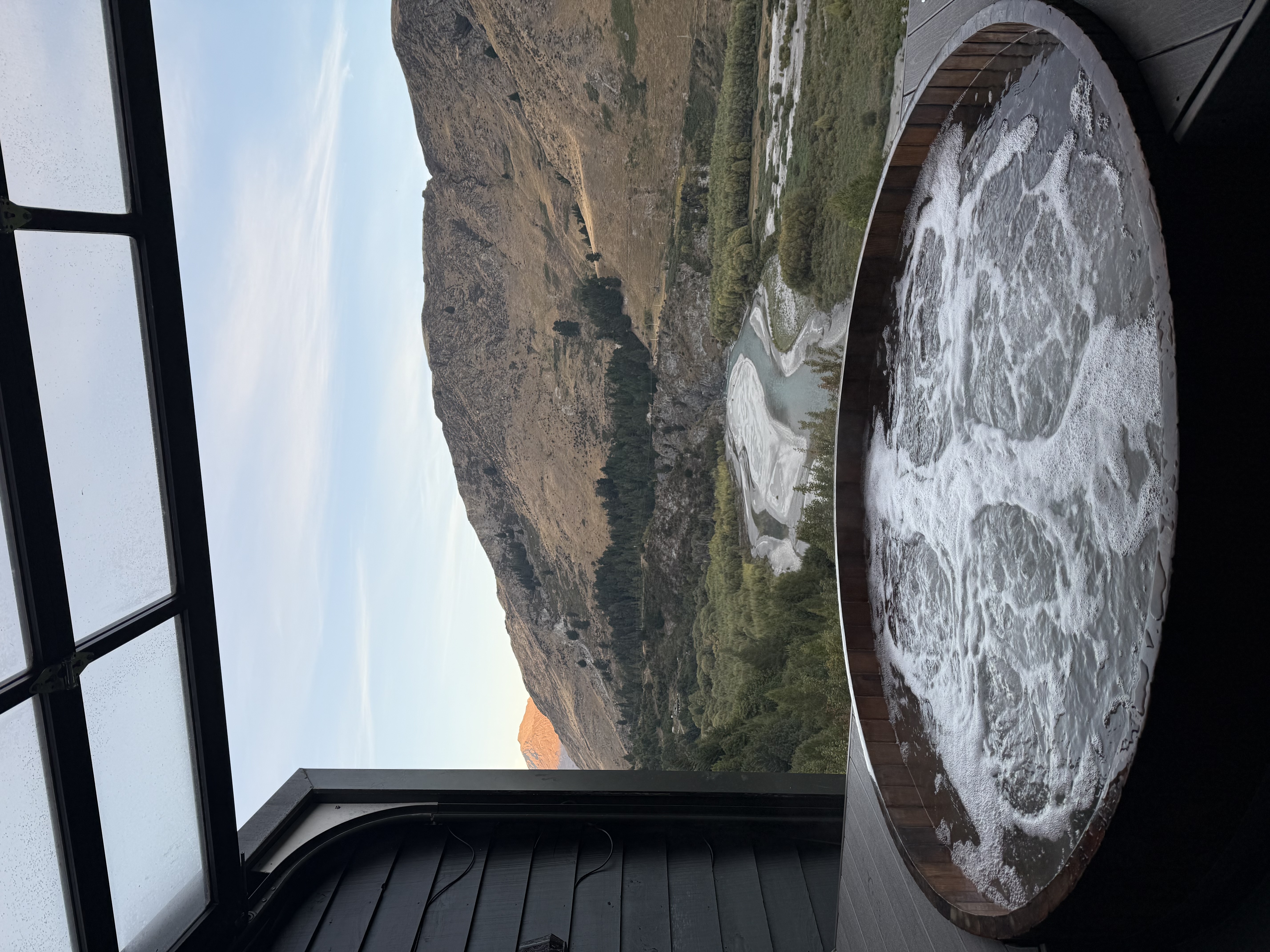 Cedar hot tub overlooking a New Zealand valley at dusk