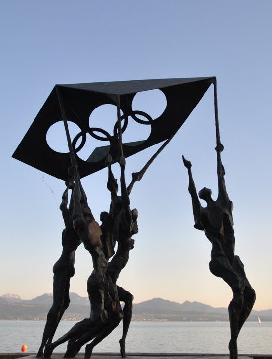 Sculpture monumentale d'athlètes brandissant les anneaux olympiques face au lac Léman