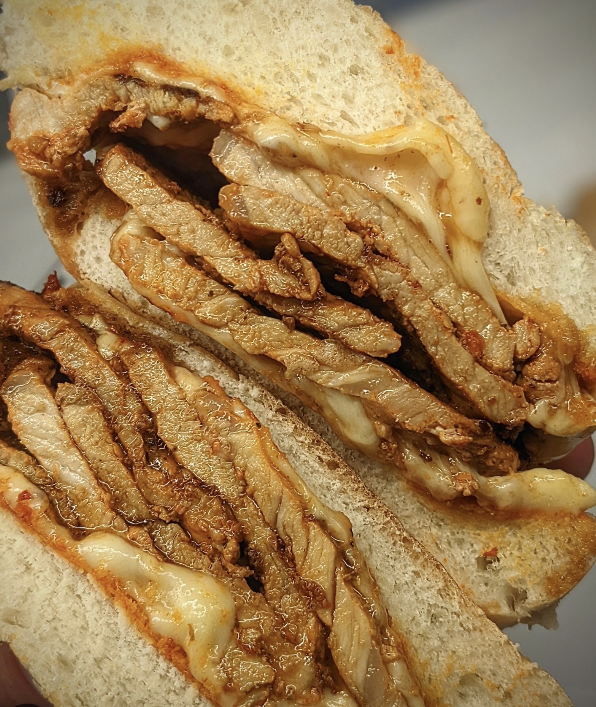 Bifana sandwich close-up, toasted bread and savory marinated pork with melted cheese