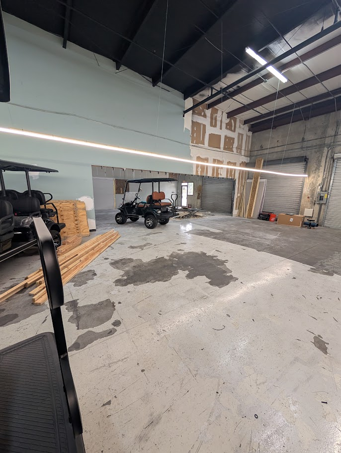 Mid-renovation shot of Jake's Custom Carts knocking down walls to combine two warehouse units into one expanded shop floor in 2025