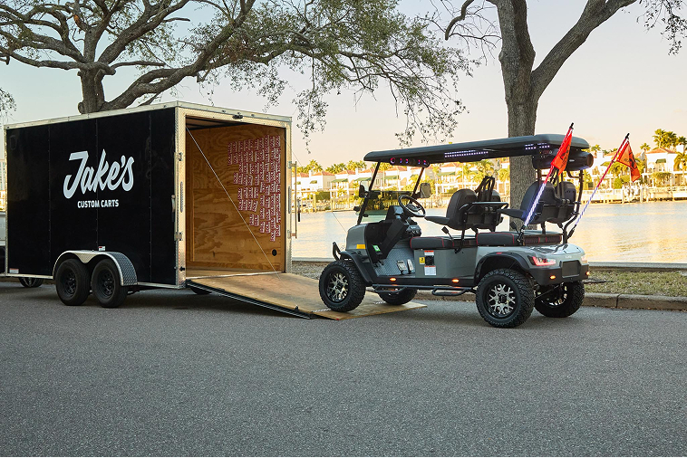Jake's Custom Carts first branded enclosed delivery trailer in 2024, unloading a gray Kandi cart at a Tampa waterfront location — the first of what is now a three-trailer fleet