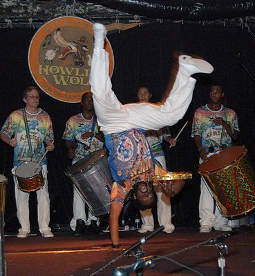 Mestre Curtis Pierre performing a handstand while playing drums