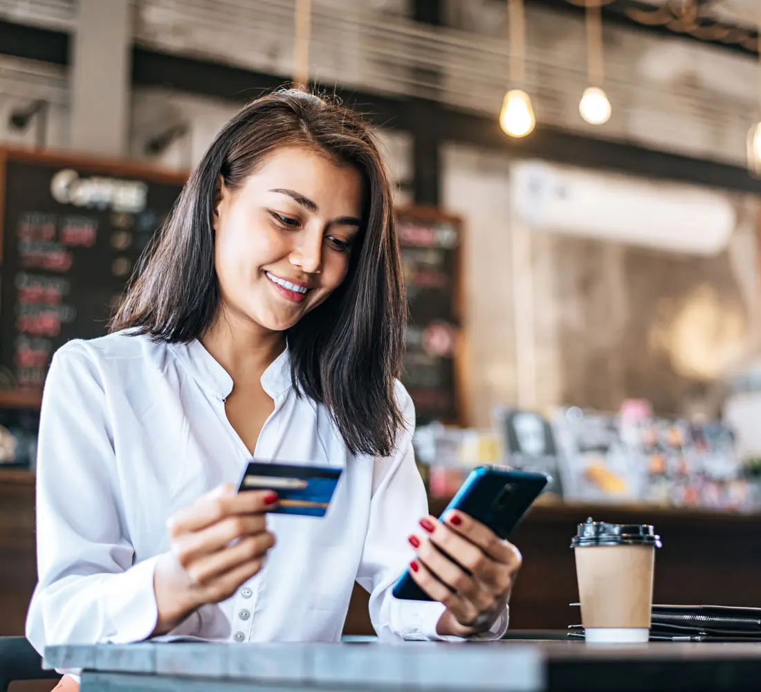 Woman making payment with credit card and phone using Authorize.net gateway