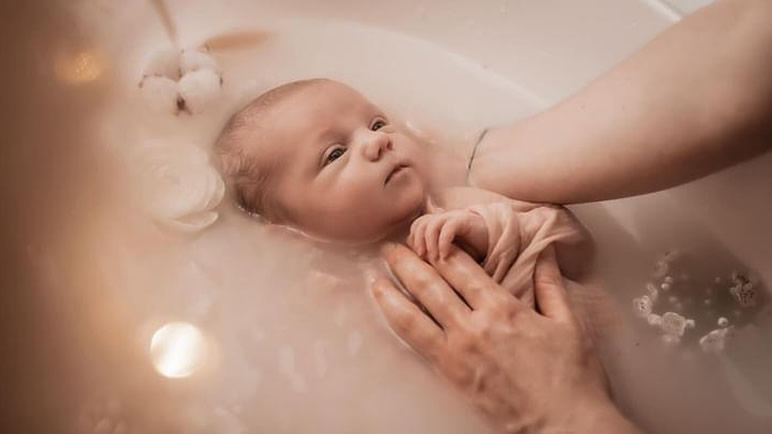 Bain enveloppé — bébé apaisé dans l'eau