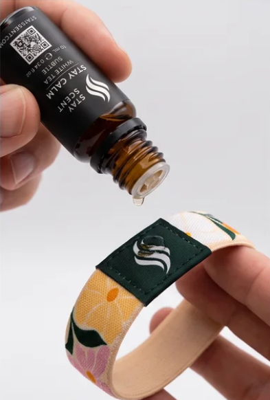 StayScent Stay Calm White Tea essential oil dripping onto a fragrance diffuser bracelet