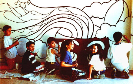 La comunità dipinge insieme: gli allievi tracciano sul muro le forme emerse dai loro stessi disegni.