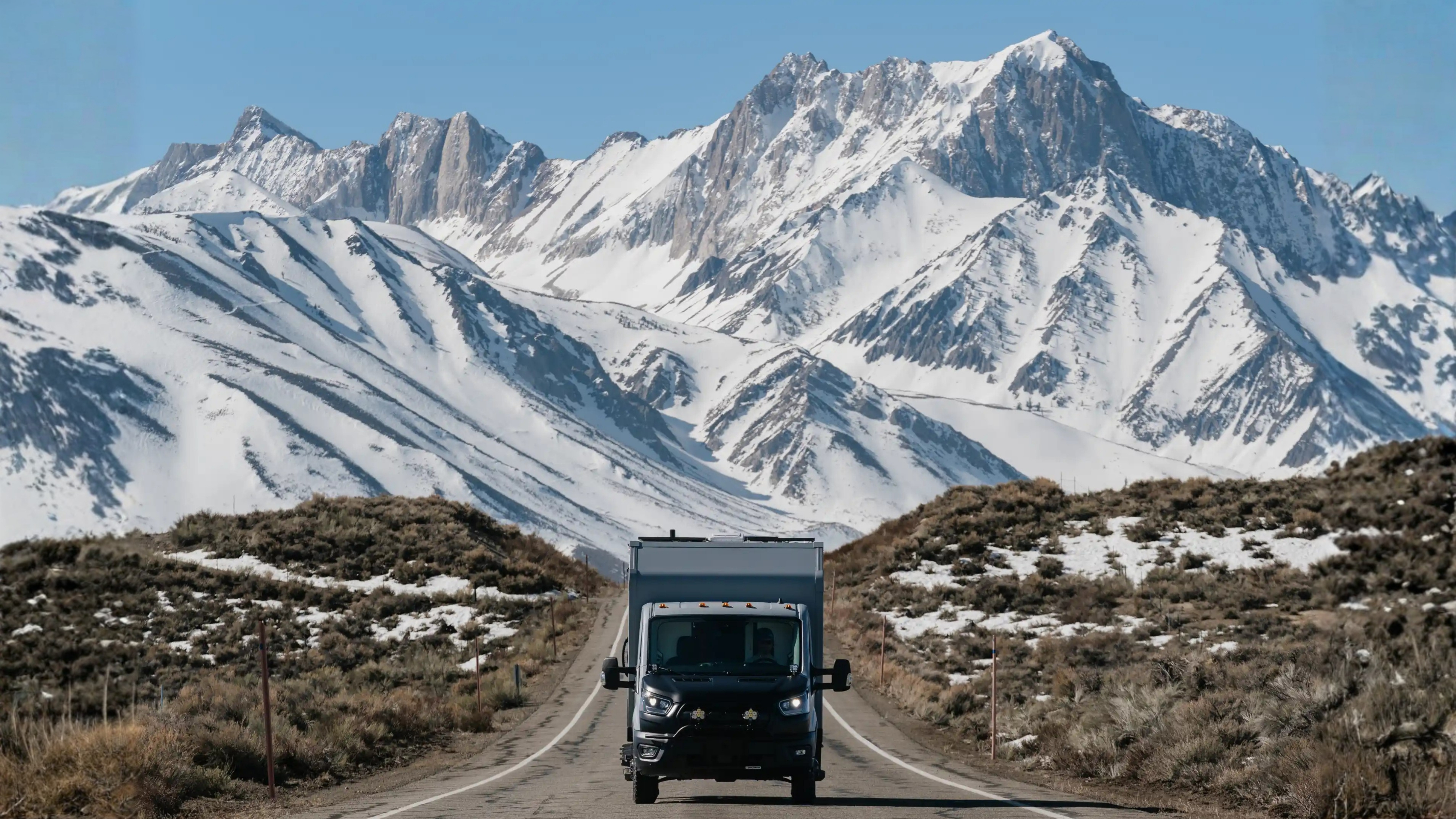 AeonRV expedition camper on mountain highway — dramatic alpine peaks