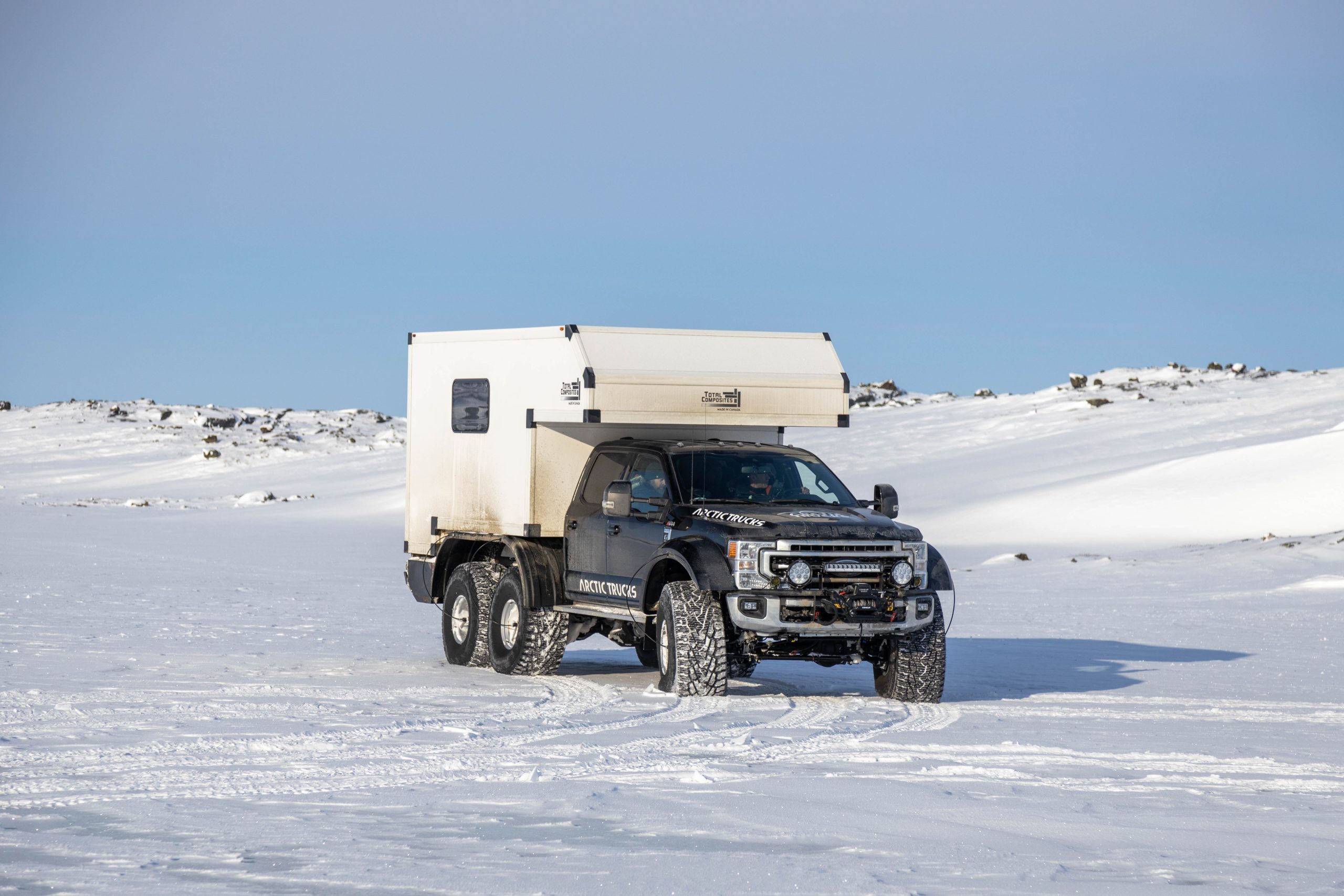 Aerial view of two AT44 trucks crossing Arctic ridge