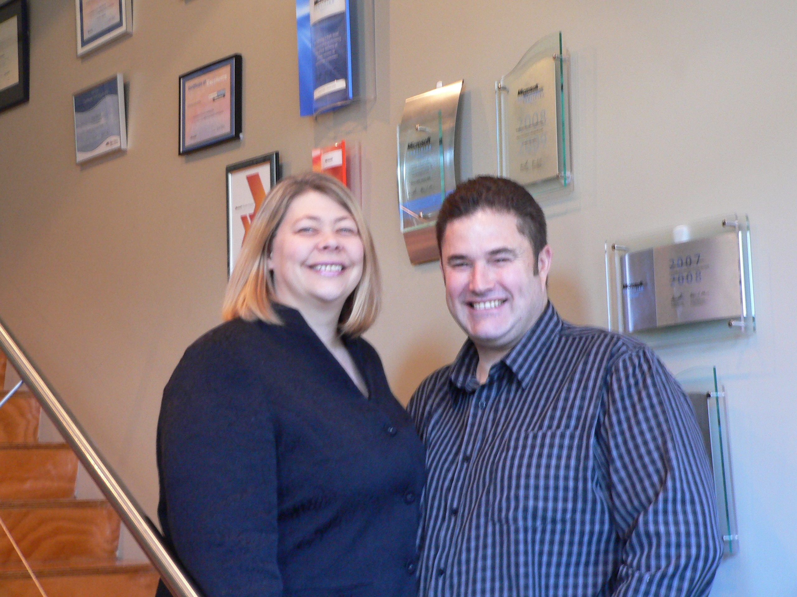 Mark and Victoria, founders of Decision1 IT Solutions, in front of the awards wall