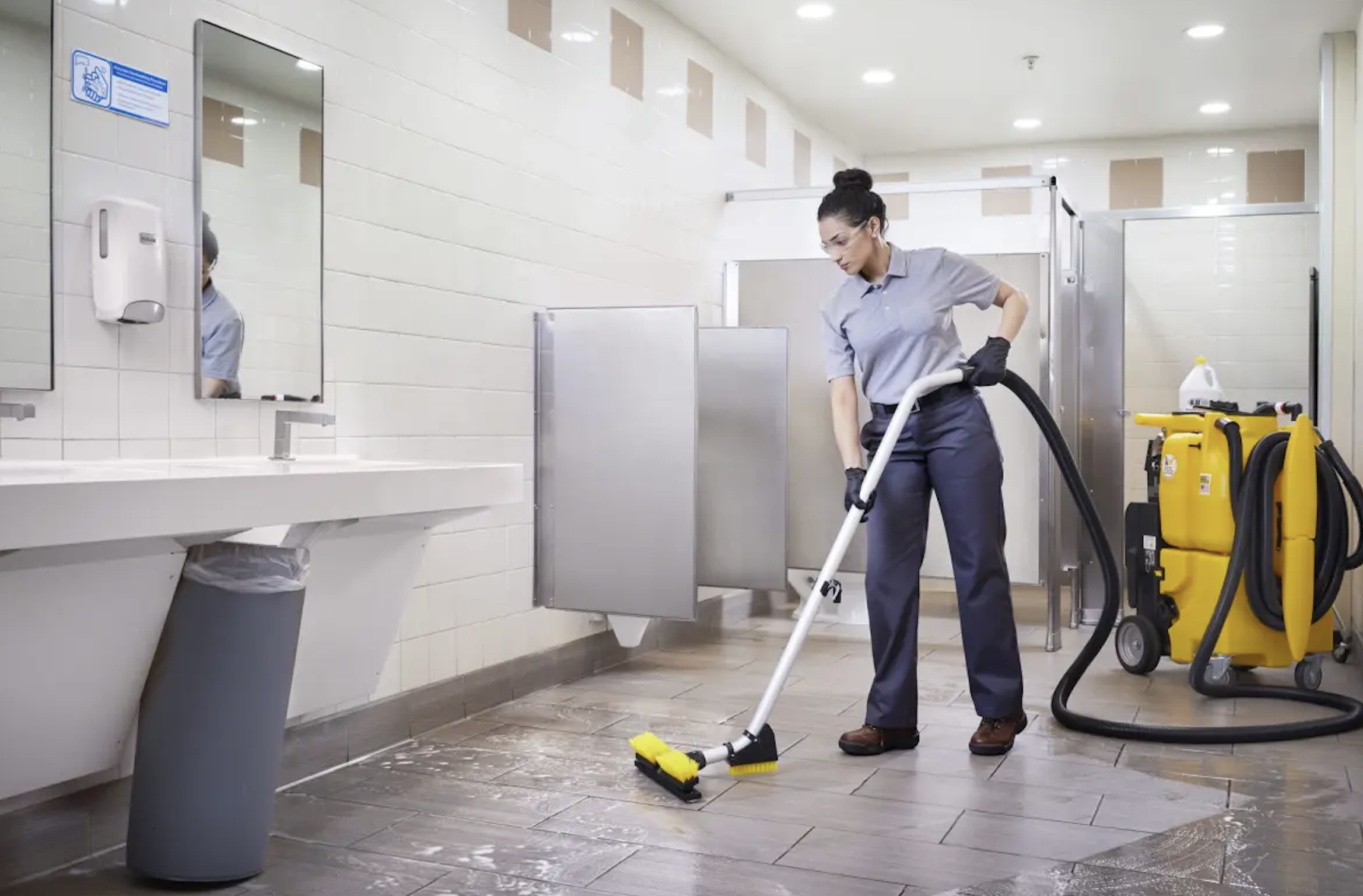 Tampa commercial cleaning technician deep scrubbing a tile restroom floor with a powered wet-vac scrubber