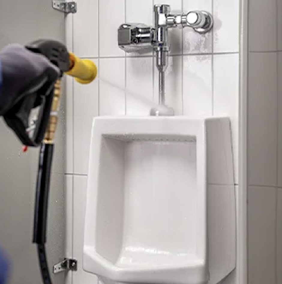 Close-up of a yellow foaming brush detailing a commercial urinal flush valve