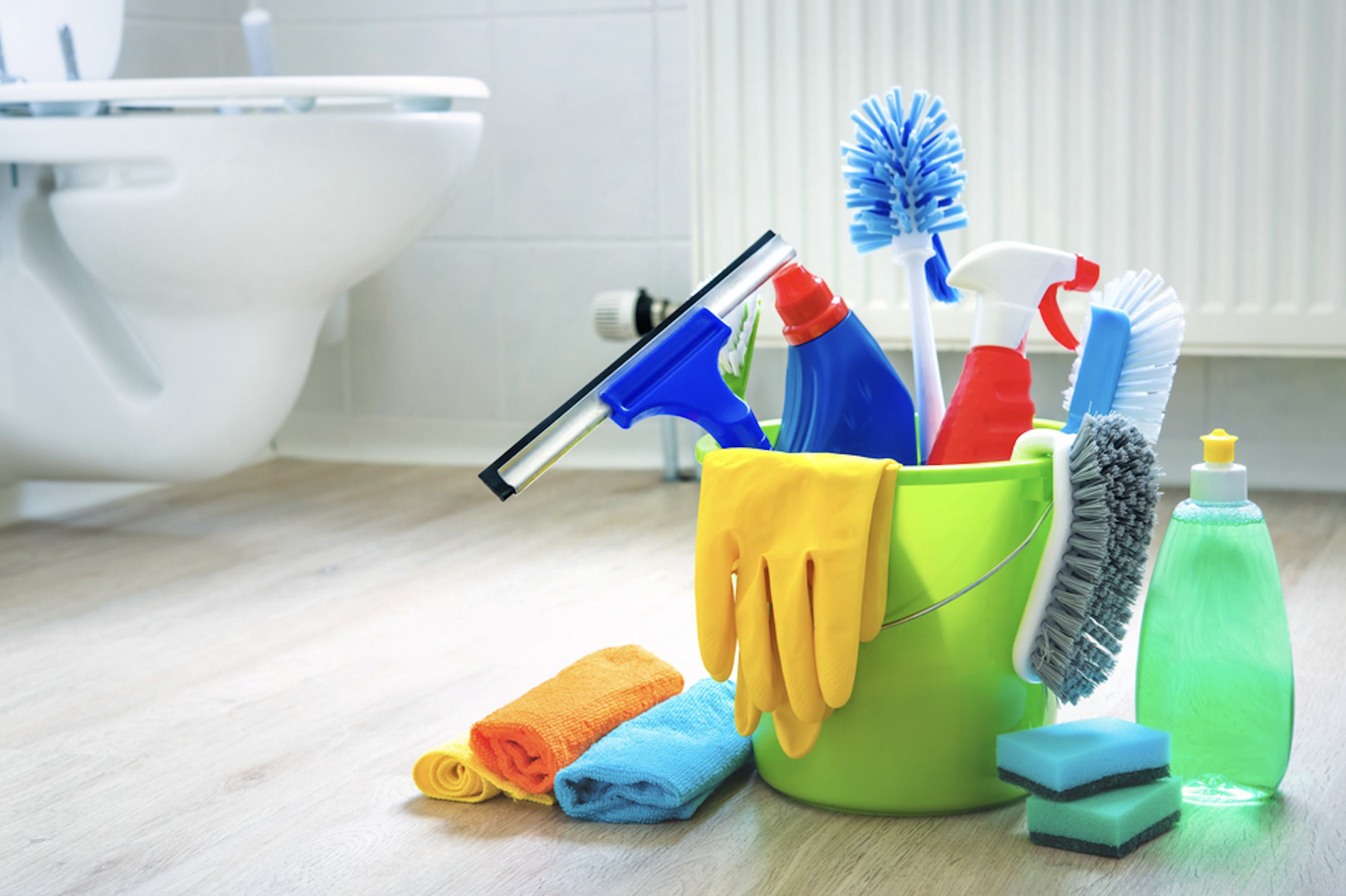 Clean white commercial toilet beside a bucket of cleaning supplies on a bathroom floor