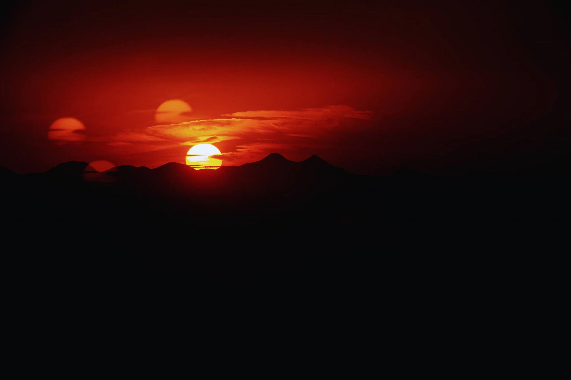 Desert sunset over silhouetted mountains