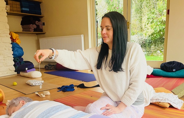 Annelie Lily using a crystal pendulum for chakra healing and energy balancing with a client
