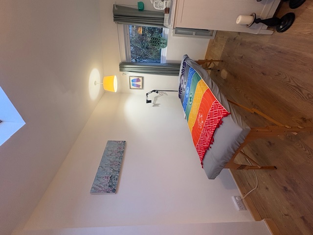 Tranquil garden room treatment space in Frome with massage table dressed in rainbow chakra blanket and natural light