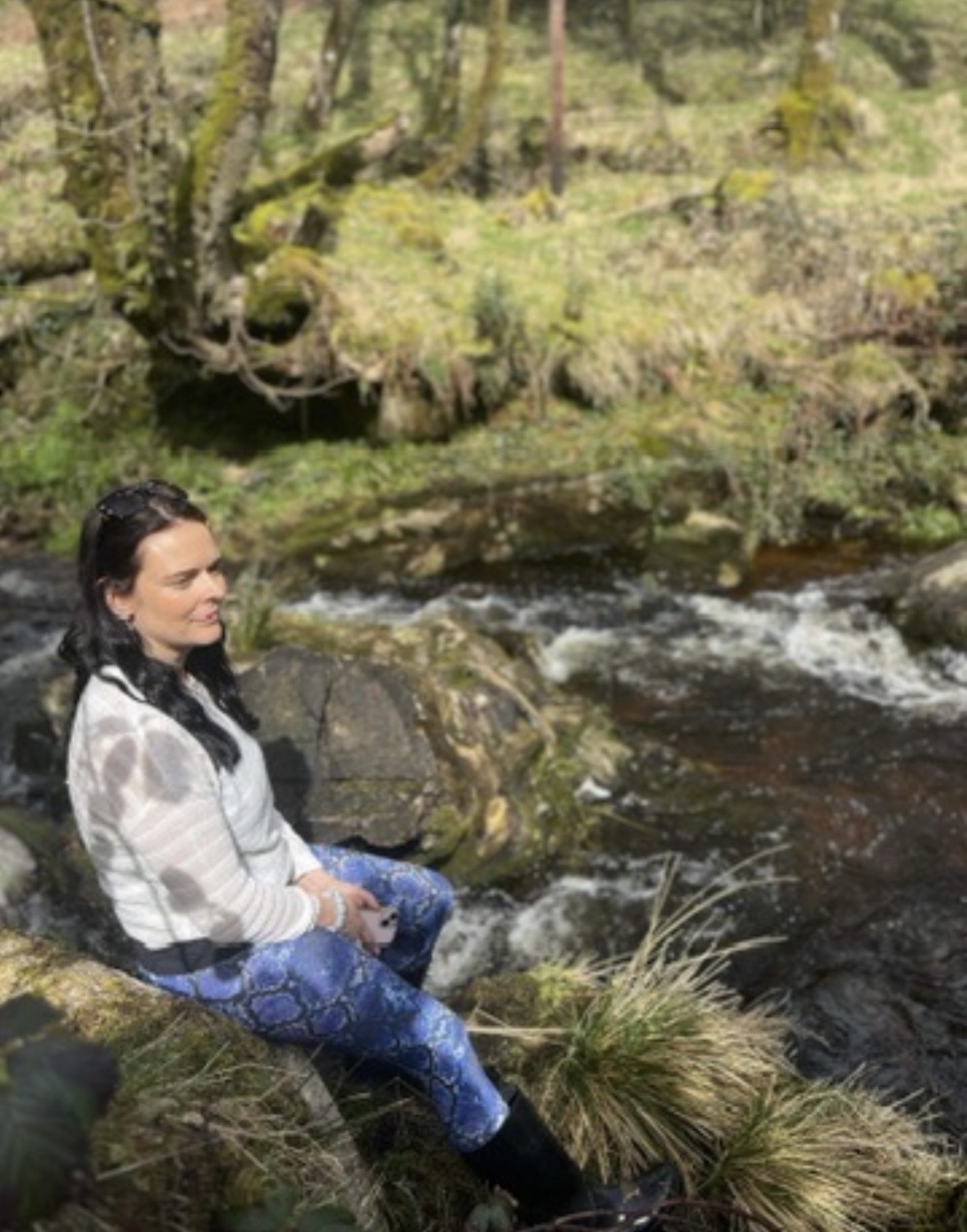 Annelie Lily sitting peacefully by a river in nature, connecting with the outdoors