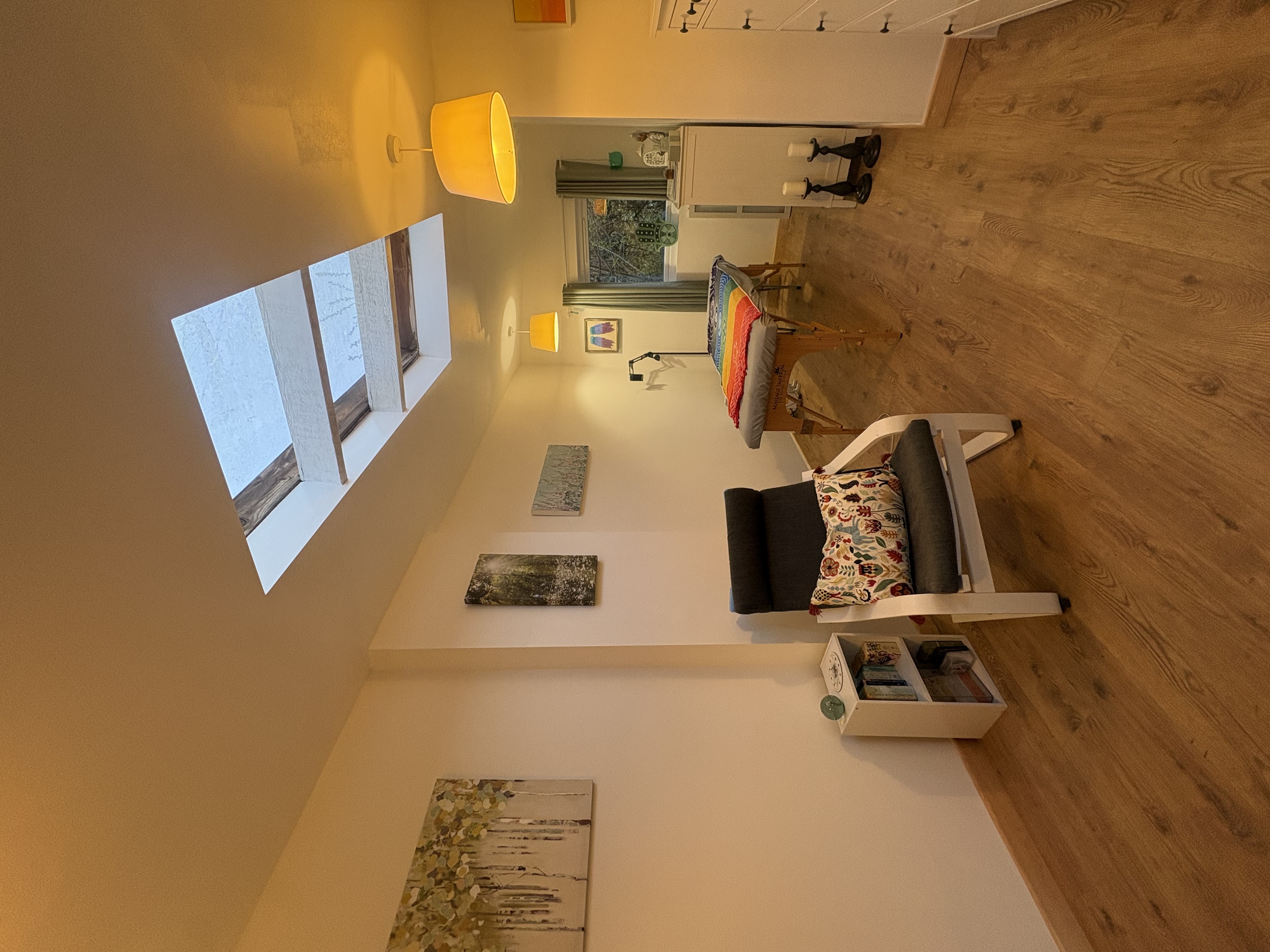 Full view of the peaceful garden room treatment space with skylight, comfortable seating area and massage table