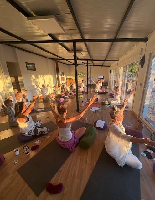 Golden hour yoga session with retreat group practicing arm stretches in Spanish studio