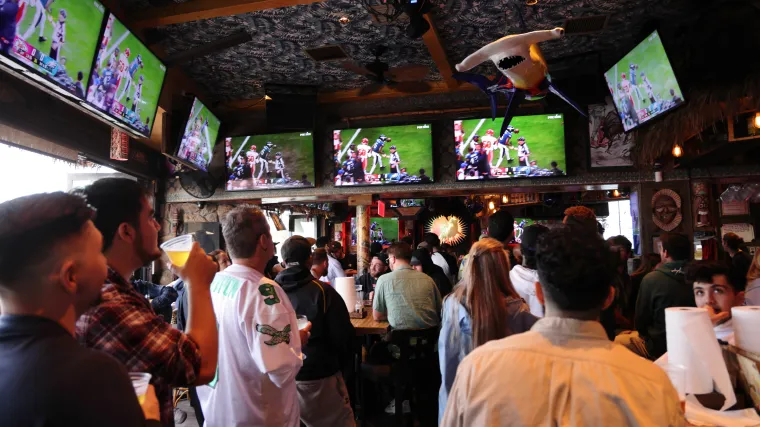 Person watching live football game while using betting app on phone