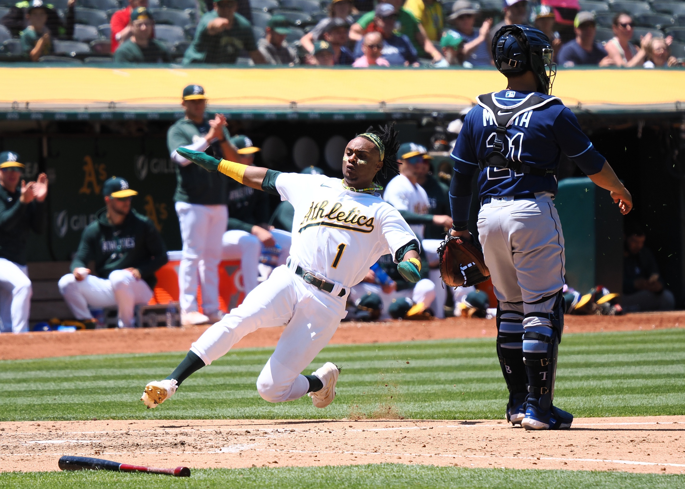 Oakland Athletics player sliding into home plate past the catcher