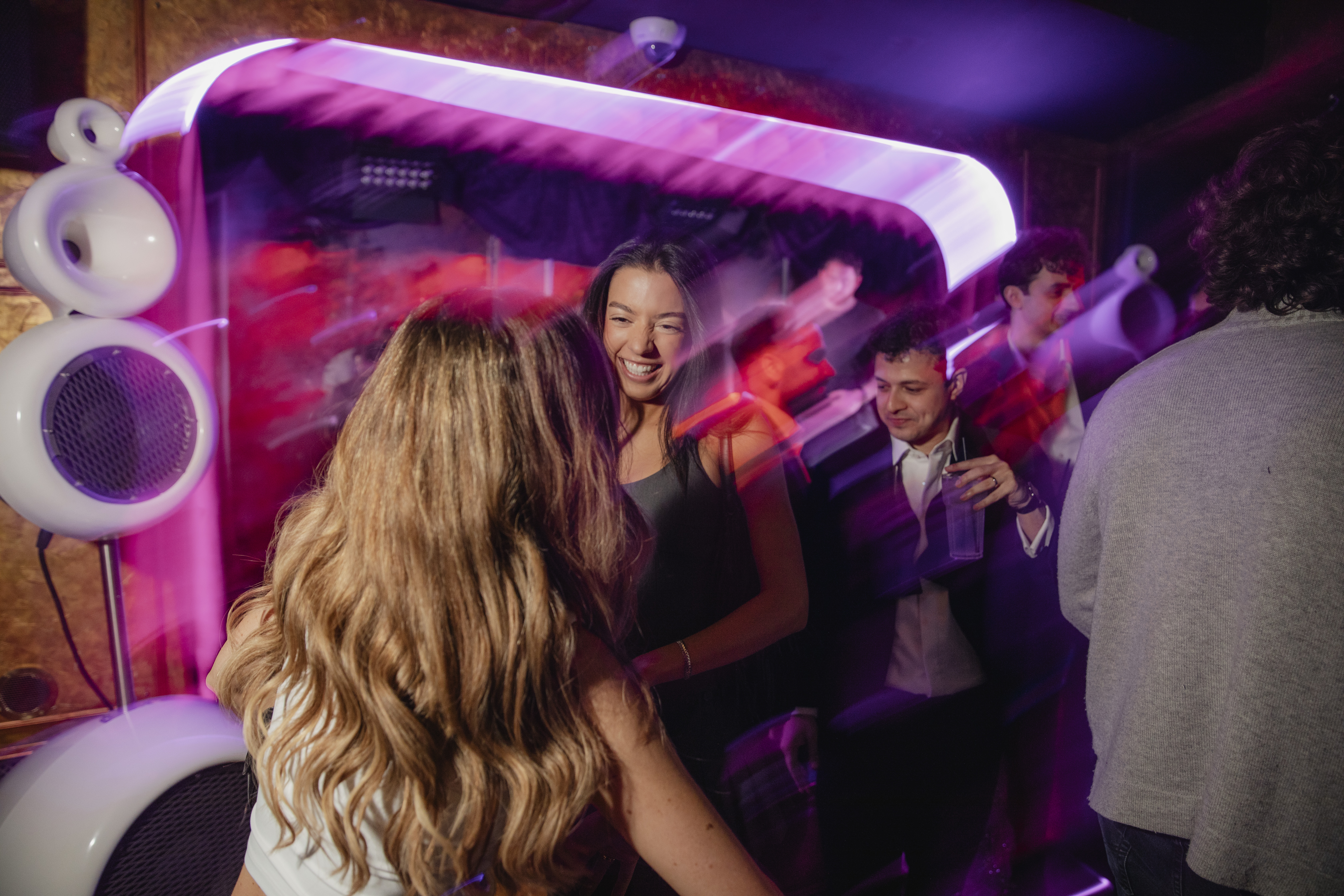 People dancing next to Vesper speakers with neon lights