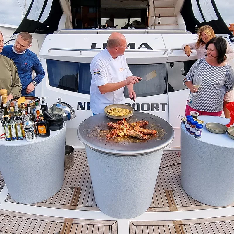 Chef cooking seafood on a round Qookingtable