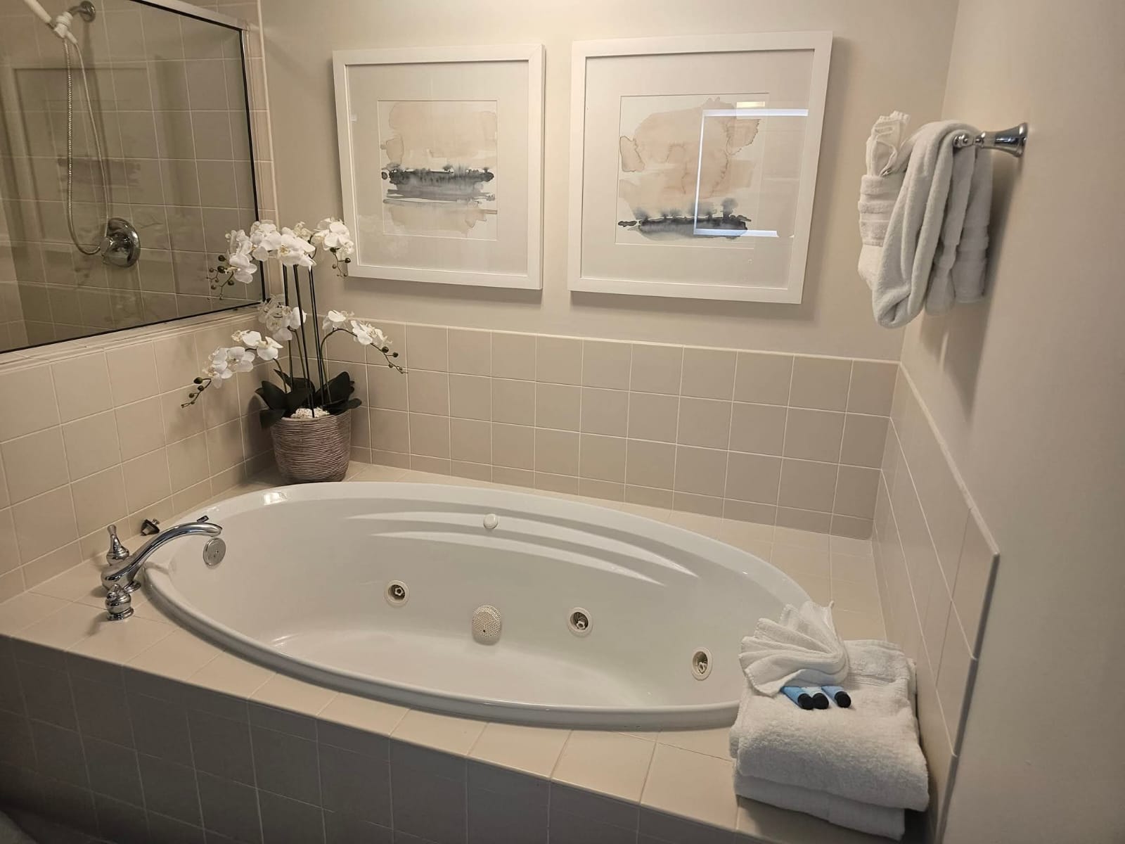 Polished jacuzzi soaking tub with neatly folded towels and fresh orchids